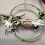 zielony wianek udekorowany białymi kwiatami z płaskim kawałkiem drewna z napisem wesołego alleluja