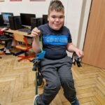 uczeń na wózku inwalidzkim prezentuje wykonaną przez siebie pracę z origami