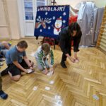 Uczniowie z Magikiem zbierają karty z podłogi.