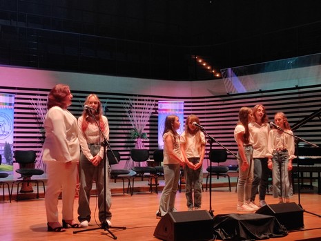 grupa siedmiu dziewcząt śpiewających do mikrofonu