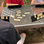 uczniowie grają na ławeczce w ogrodzie w grę planszowa