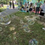 Zdjęcie przedstawia społeczność szkolną wśród mydlanych baniek