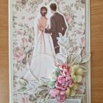 kartka okolicznościowa z okazji ślubu wykonana techniką scrapbookingu z bukietem kwiatów z parą młodą odwróconą plecami z różowymi kwatami