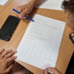 uczniowie rozwiązują zagadki logiczne na kartce papieru
