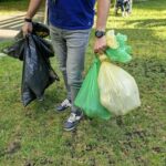 mężczyzna niesie w obu rękach worki pełne śmieci