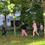 czworo uczniów maszerujących z workiem na śmieci i szukający śmieci w ogrodzie