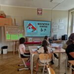uczniowie siedząc w ławkach oglądają prezentację dotyczącą powstania warszawskiego