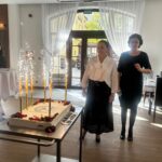 pani dyrektor i pani kierownik stoją przy jubileuszowym torcie na którym palą się race
