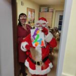 Święty Mikołaj pokazuje pracę plastyczna wykonaną przez jedną z uczennic.