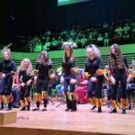 uczniowie szkoły muzycznej występują na scenie w tle widać orkiestrę dentą