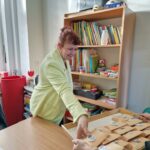 kobieta w zielonej marynarce zdejmuje z tacy prezent