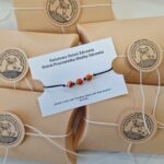 zdjęcia przedstawia bransoletkę wyplecioną z czarnego sznurka z trzema czerwonymi koralikami