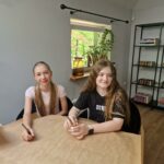 uczennice siedzą przy stoliku i czekają na rozpoczęcie się konkursu