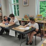 uczniowie siedzą i w zespołach rozwiązują zadania